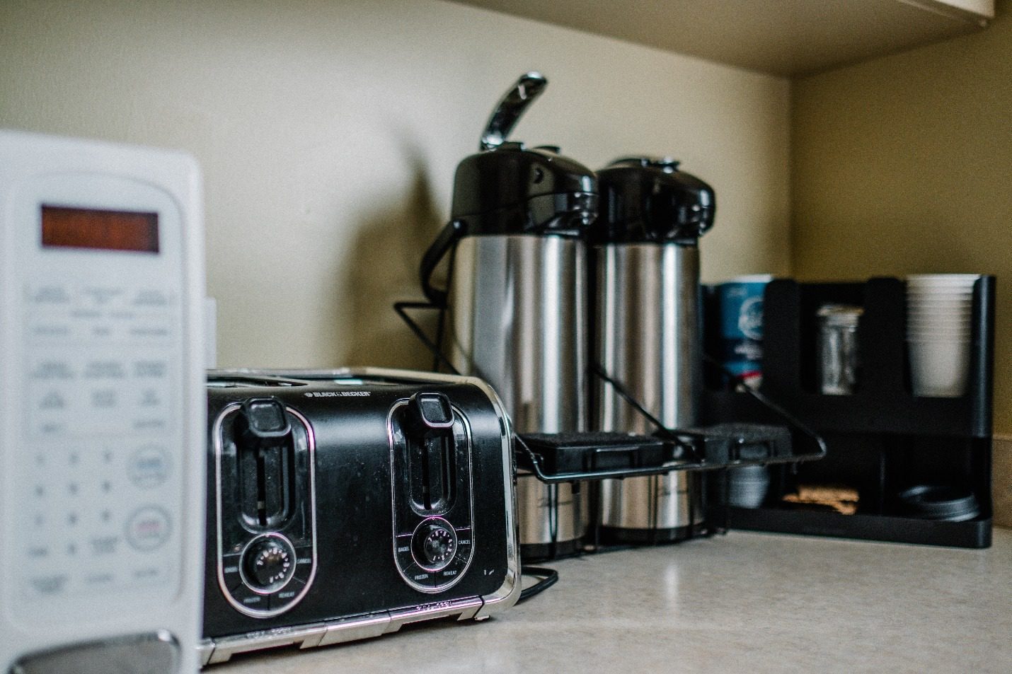 A coffee maker and coffee cans on a counterDescription automatically generated