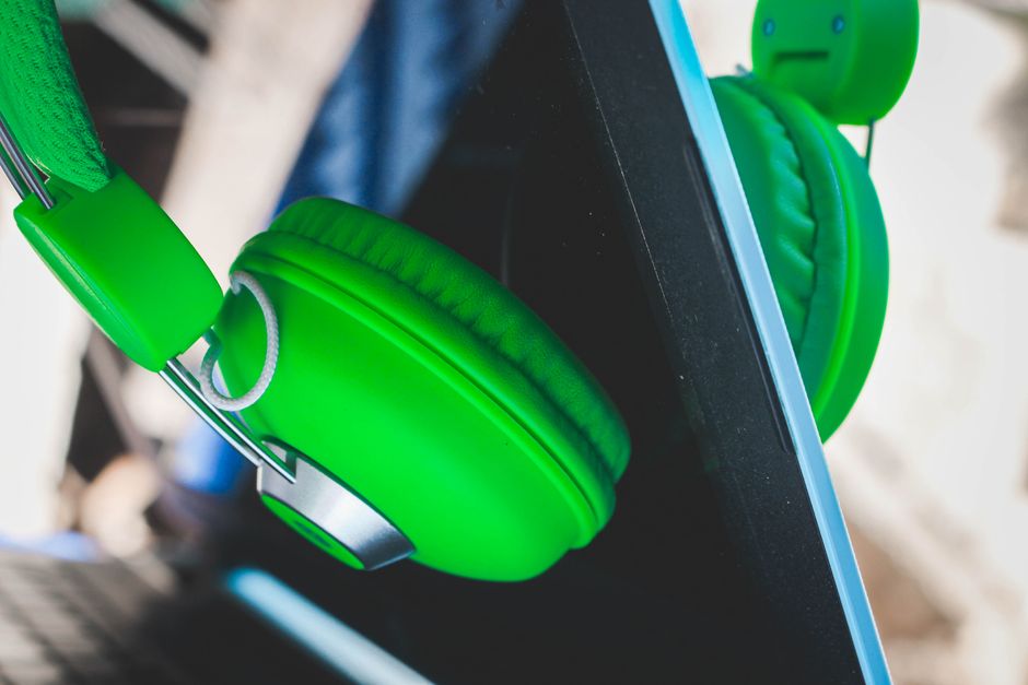 Green wireless headphones on a table beside a laptop