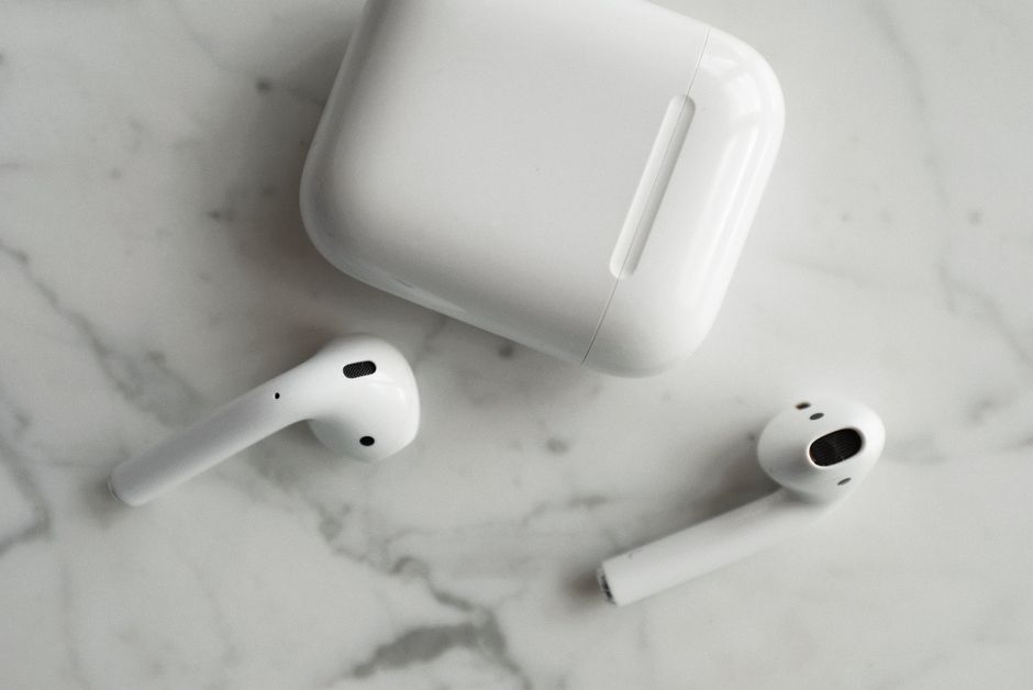 Wireless earbuds lying next to an open charging case