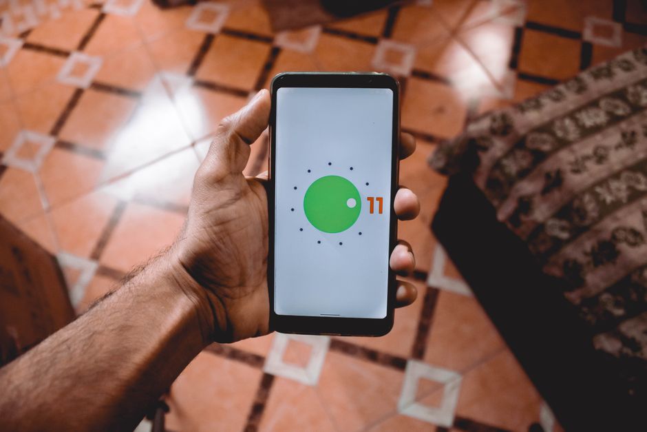 Hand holding an Android phone displaying its home screen interface