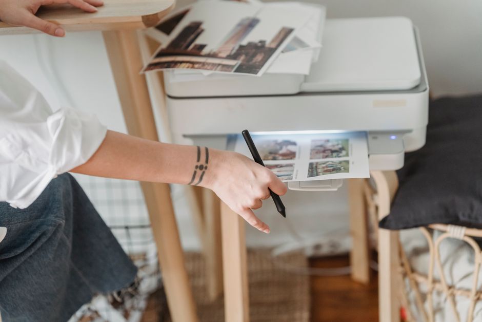 Person adjusting printer settings while standing beside a home printer