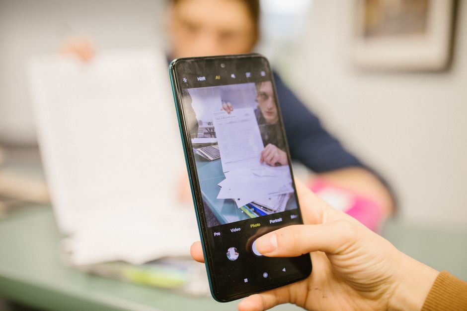 Person using a smartphone camera to photograph a paper document