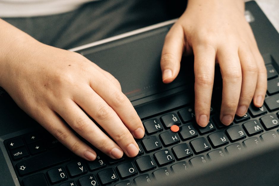 Hands typing on a black laptop keyboard