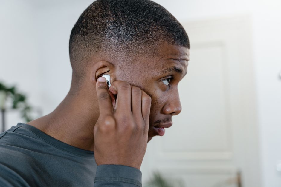 Man adjusting a wireless earbud in his ear indoors