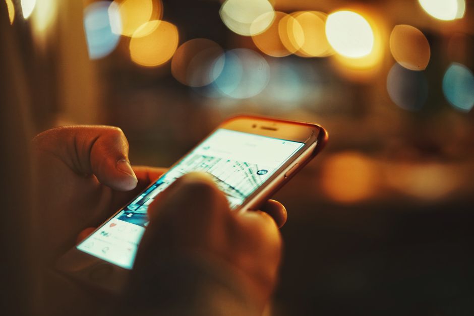 Hand holding a smartphone against a warm bokeh background