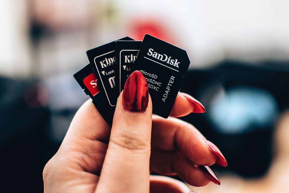 Hand holding microSD memory cards over a laptop