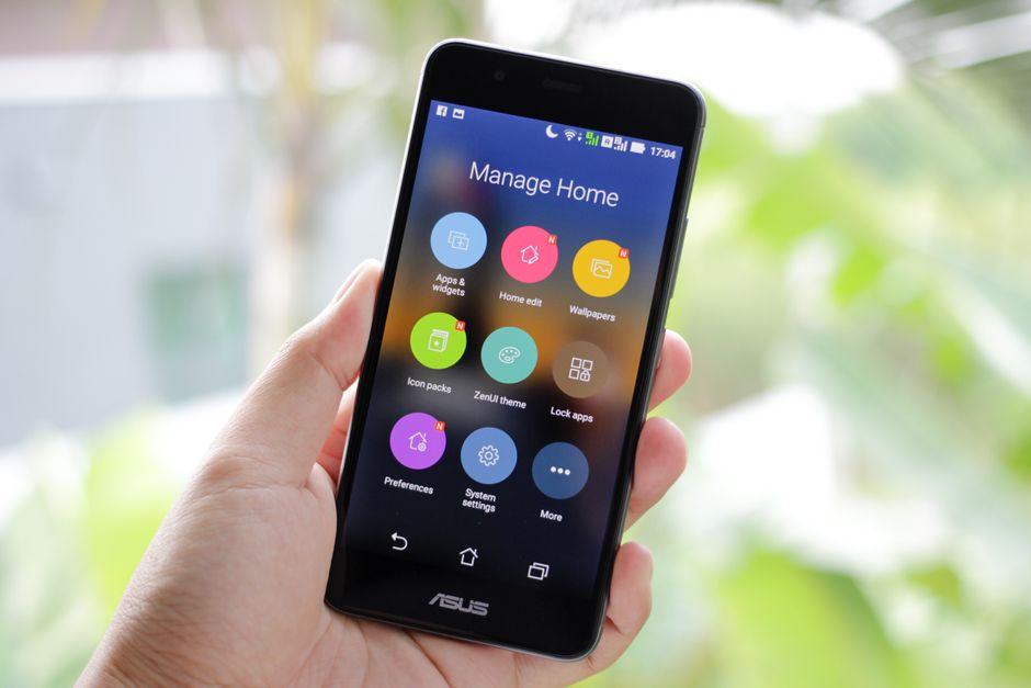 Hand holding a smartphone showing apps on the home screen