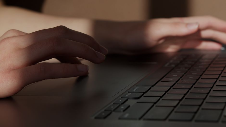 Person using a laptop touchpad at a table at home