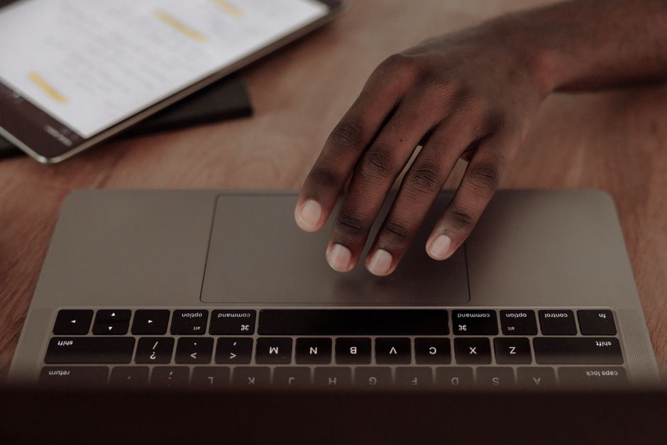 Hand interacting with a laptop touchpad next to a tablet