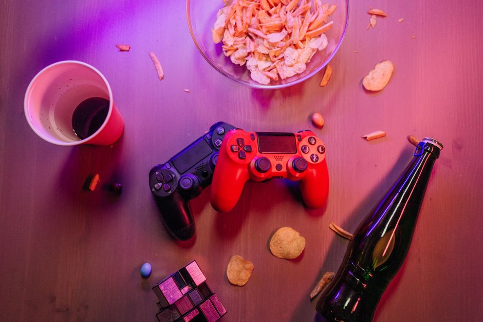 Top view of a gaming setup with controllers, snacks, and drinks, perfect for a cozy game night.